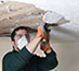 Worker removing stucco from ceiling.